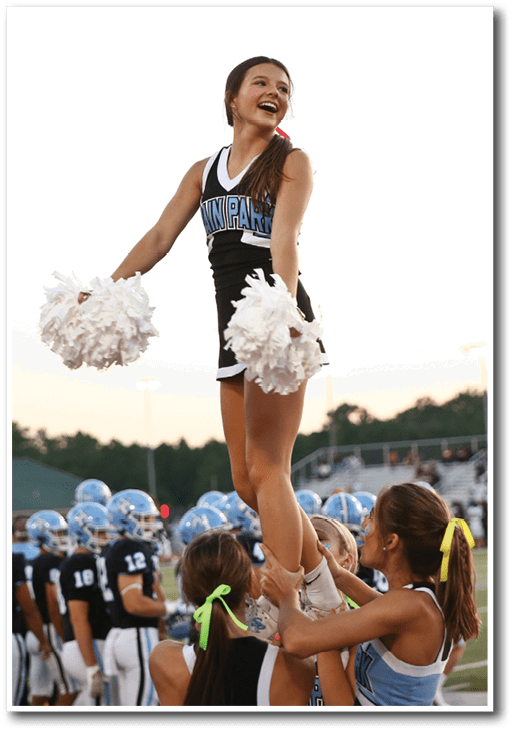 A cheerleader is lifted by her teammates, smiling as she is carried on their shoulders. AI generated content