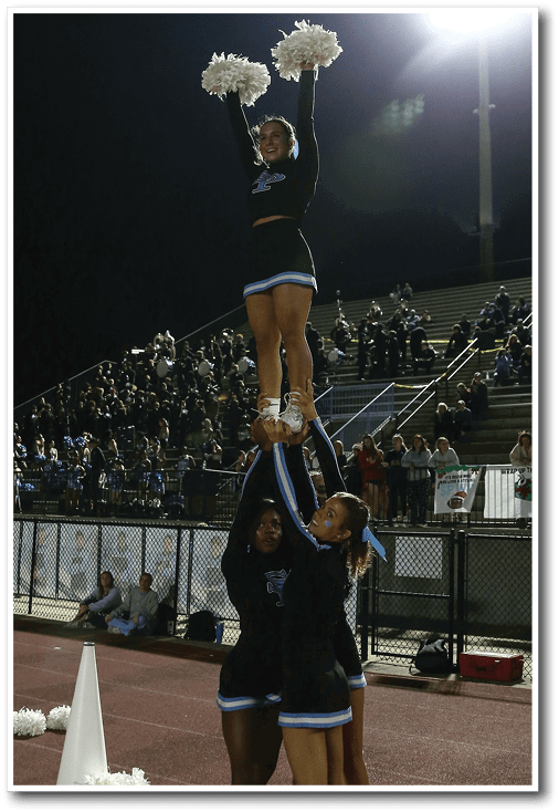 Three cheerleaders perform a stunt on a football field. AI generated content