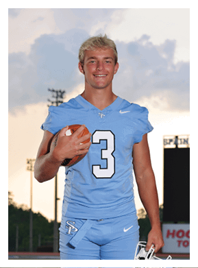 A football player in a blue uniform stands on a field holding a football. AI generated content