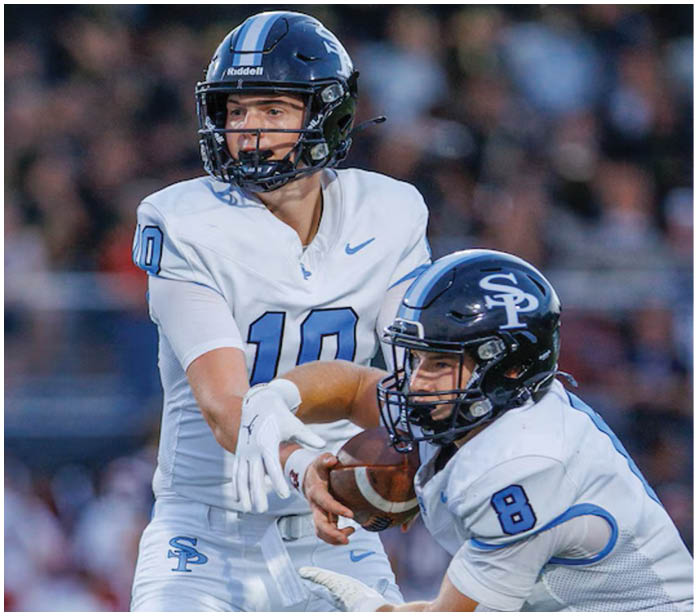 Two football players on a field, one holding a football. AI generated content