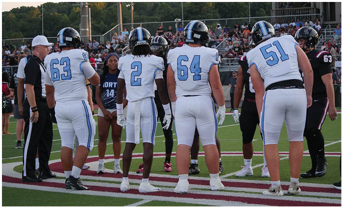 A group of football players in white uniforms stand on a field. AI generated content