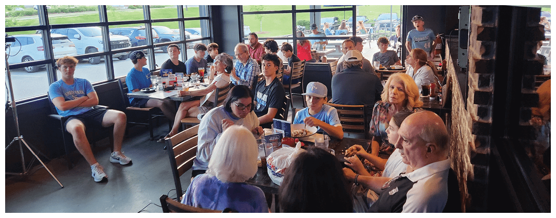 A group of people are sitting in a restaurant, enjoying their meal. AI generated content