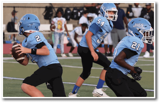 Three young boys wearing blue jerseys are running on a field, each holding a football. AI generated content