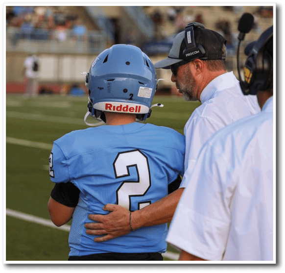 A football player wearing a blue helmet is being patted on the back by a coach. AI generated content