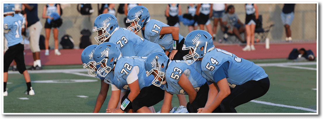 A group of football players in blue uniforms are lined up on the field, getting ready for a play. AI generated content