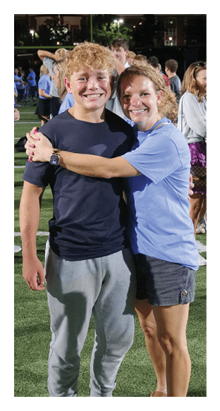 Two people hugging on a field with a group of people in the background. AI generated content