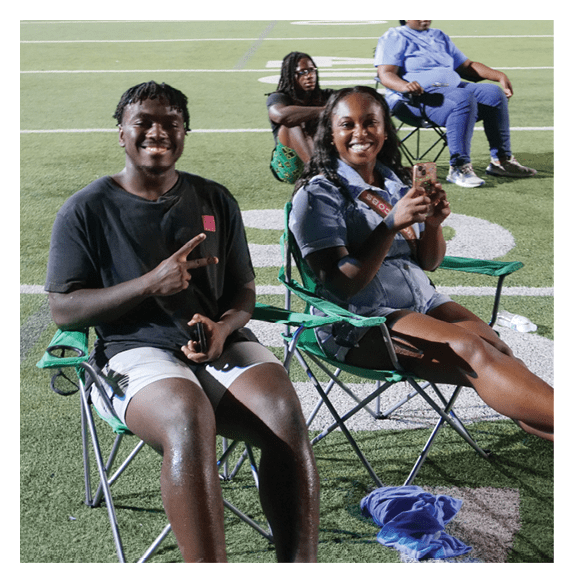 Two people are sitting on chairs on a field, smiling and enjoying their time together. AI generated content