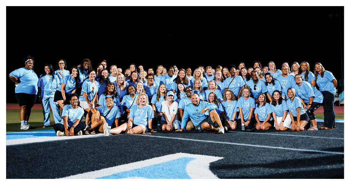 A group of people wearing blue shirts pose for a photo on a field. AI generated content