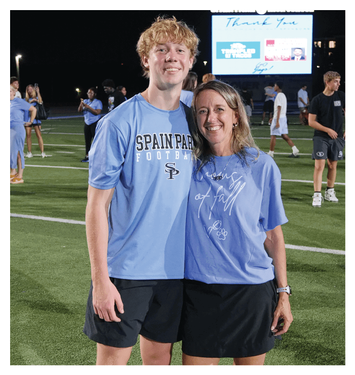 A man and woman are standing on a field, both wearing blue shirts. They are posing for a picture. AI generated content