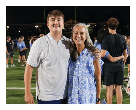 A man and woman are standing on a field, posing for a picture. The woman is wearing a blue and white dress. AI generated content