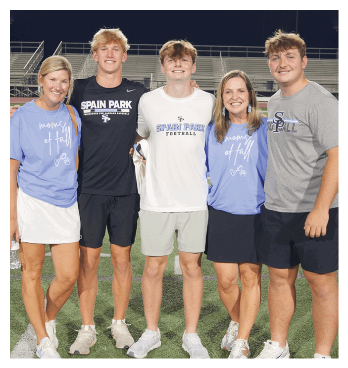 A group of five people, including a man and a woman, pose for a photo on a football field. AI generated content
