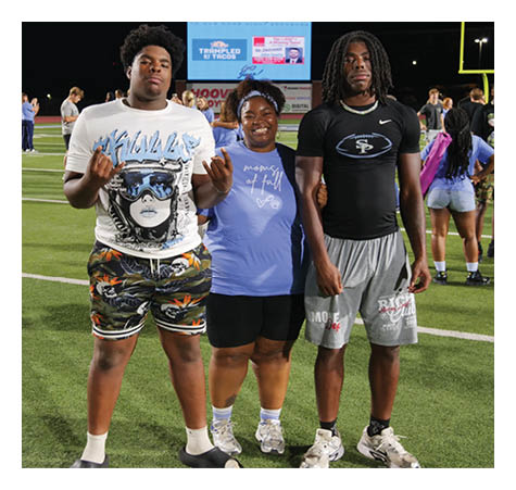 Three people are standing on a field, posing for a picture. Two of them are wearing shorts, and one of them is wearing a black shirt. AI generated content