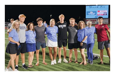A group of people posing for a picture on a football field. AI generated content