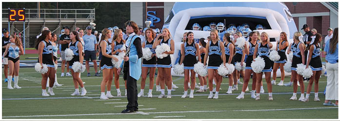 A group of cheerleaders in blue and white uniforms are standing on a field. AI generated content