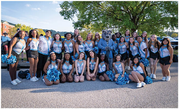 A group of cheerleaders pose for a picture in front of a tree. AI generated content