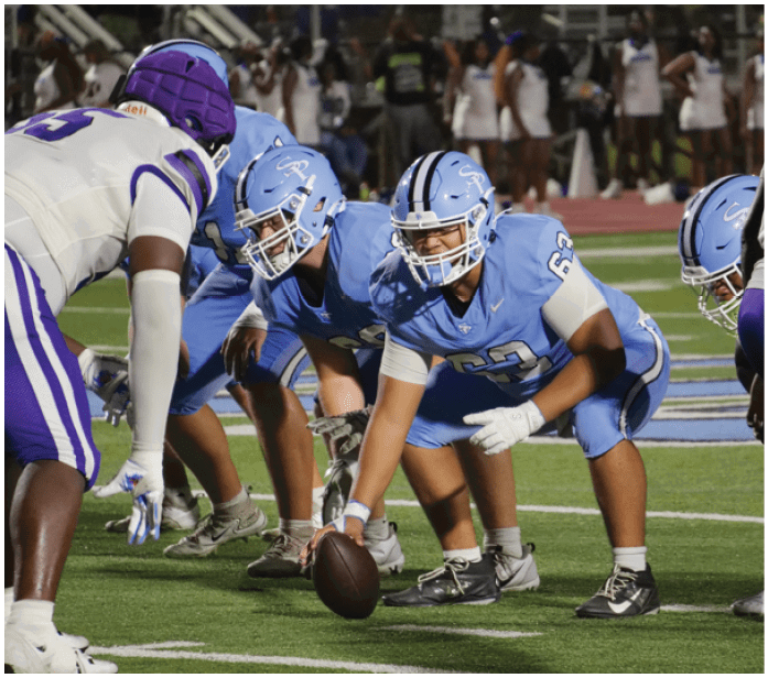 A group of football players in blue uniforms are on the field. AI generated content