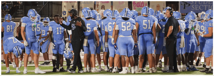 A group of football players in blue uniforms are gathered on the field. AI generated content