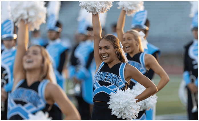 A group of cheerleaders in uniforms are performing on a field. AI generated content