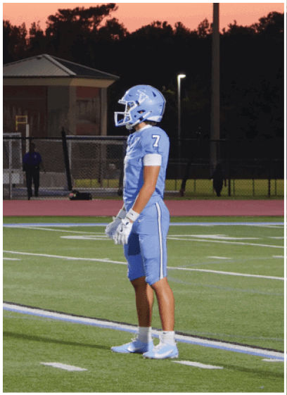 Three football players are standing on a field, wearing blue uniforms. They are waiting for the play to start. AI generated content