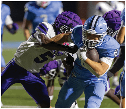 Two football players are running on the field, one wearing a blue jersey and the other wearing a white jersey. The blue player is trying to tackle the white player who is holding a football. AI generated content