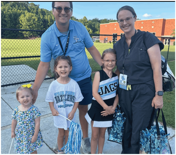 A man, woman, and two children pose for a picture. The woman is holding a bag. AI generated content