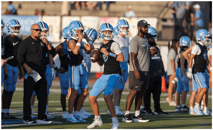 A group of football players are standing on a field, some holding footballs. AI generated content