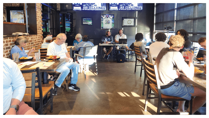 A group of people are sitting in a restaurant, watching TVs on the wall. AI generated content