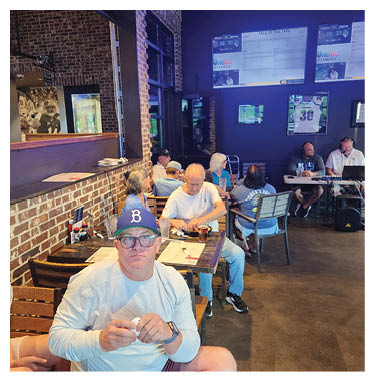 A man wearing a white shirt and a blue hat is sitting at a table in a restaurant. AI generated content