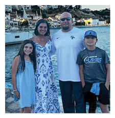 A man, woman, and two children pose for a photo in front of a body of water. AI generated content