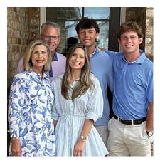 A family of four poses for a photo in front of a brick wall. AI generated content