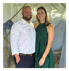 A man and woman pose for a picture in front of a sign that says “Happy Ever After". AI generated content