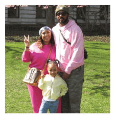 A man, woman, and child pose for a photo in a park. The woman is wearing pink and holding a handbag. The man is wearing a pink hoodie. AI generated content