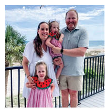 A family of four poses for a photo on a deck near the ocean. AI generated content