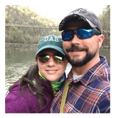A man and woman are standing next to each other, posing for a photo. The man is wearing a plaid shirt and sunglasses, while the woman is wearing a hat. They are both smiling and enjoying their time together. AI generated content