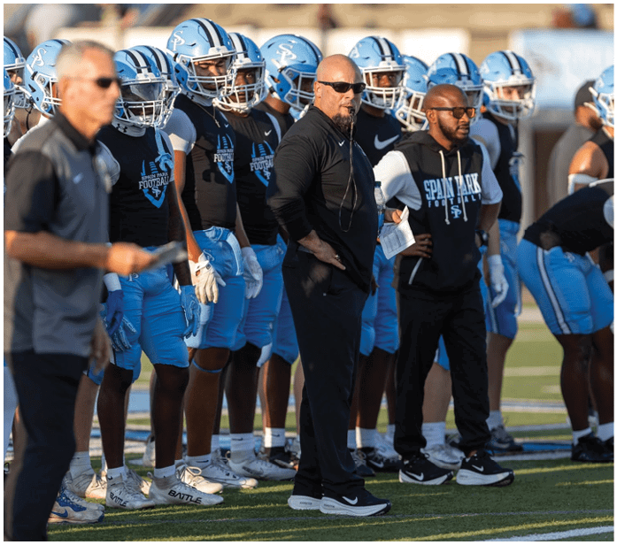 A group of football players wearing blue and white uniforms are standing on a field. AI generated content