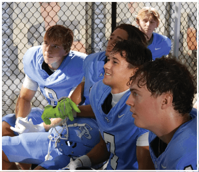 A group of young men wearing blue jerseys are sitting on a bench. AI generated content