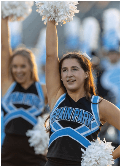 Two cheerleaders in uniforms are holding pom poms and smiling. AI generated content