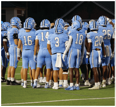 A group of football players wearing blue uniforms and white socks are standing on a field. AI generated content