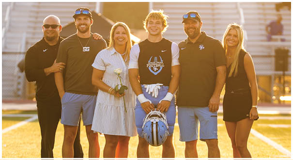 A group of people, including a man and a woman, pose for a picture on a football field. AI generated content