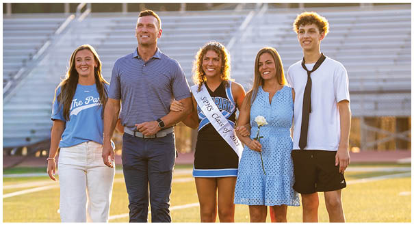 A group of people, including a man and a woman, are standing on a field. The woman is holding a rose. AI generated content