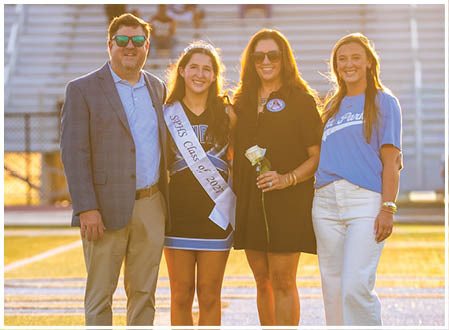 A group of four people, two men and two women, are standing on a football field. They are posing for a picture, with one of the women holding a rose. AI generated content