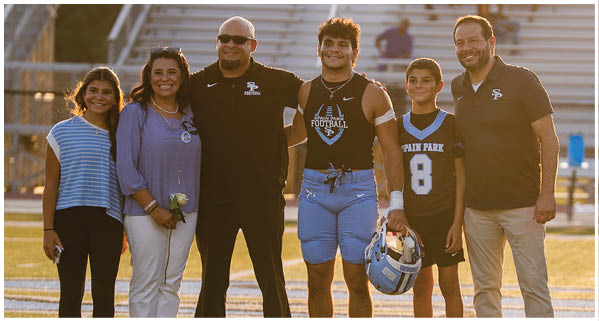 A group of people, including a football player, pose for a photo on a field. AI generated content