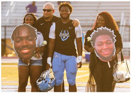 A group of people, including a football player, pose for a photo on a field. AI generated content