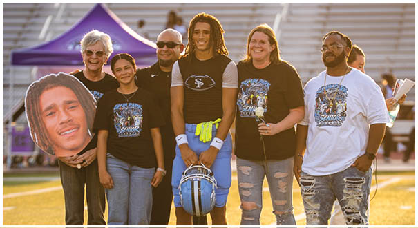 A group of people are standing on a field, posing for a picture. They are wearing shirts and holding footballs. AI generated content