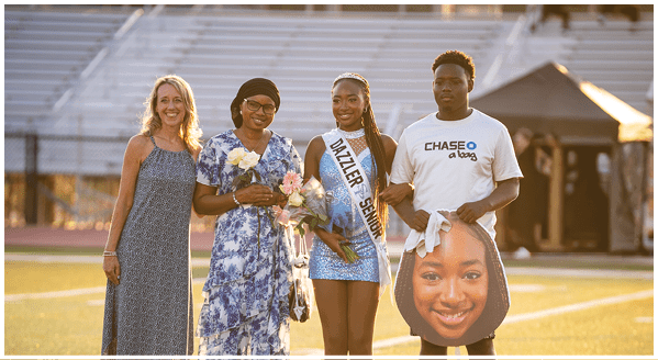 A group of people, including a woman holding flowers, pose for a picture on a field. AI generated content