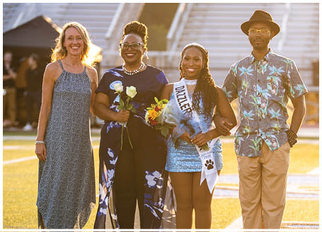 A group of people, including a woman wearing a crown, pose for a photo on a field. AI generated content