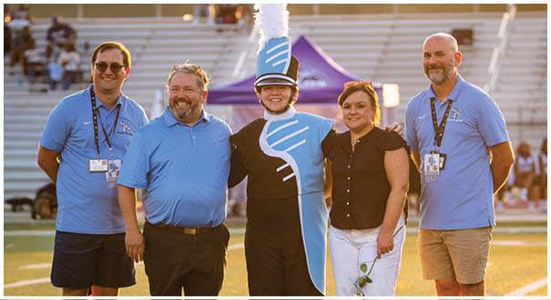 Four people pose for a picture on a field. AI generated content