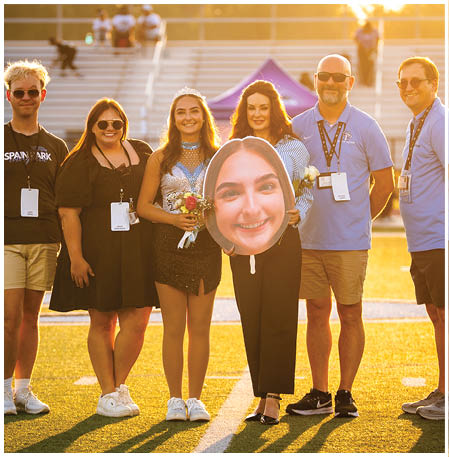 A group of people posing for a photo on a football field. AI generated content