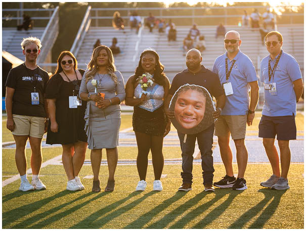 A group of people posing for a photo on a football field. AI generated content
