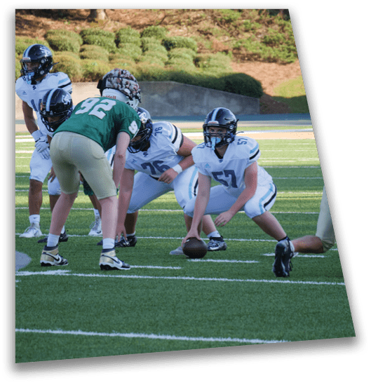 A group of football players in uniforms are on the field, with one player holding a football. AI generated content